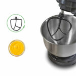 Stand mixer with metal bowl and beater attachment, plus a small jar of yellow mustard-like cream to the left and a circular green logo above the cream on the left side of the image.
